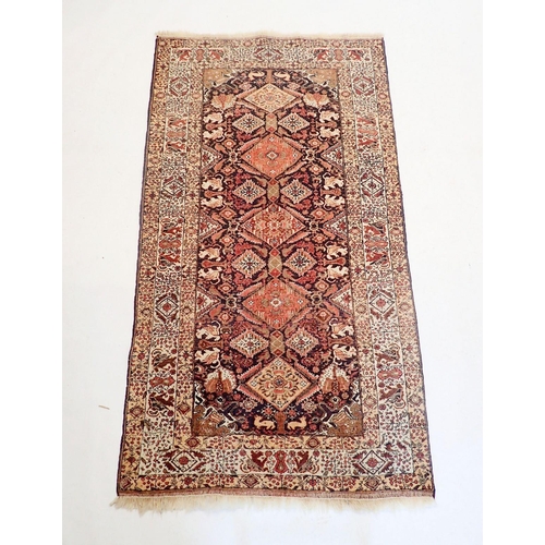 1323 - A Persian style rug with coral red and blue lozenge design, 181 x 100cm