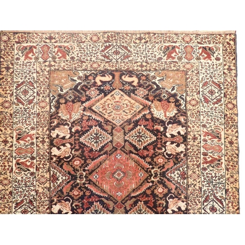 1323 - A Persian style rug with coral red and blue lozenge design, 181 x 100cm