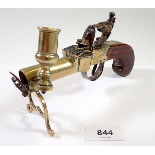 844 - An antique percussion action pistol table lighter with taper stick, 17cm long and a brass stirrup