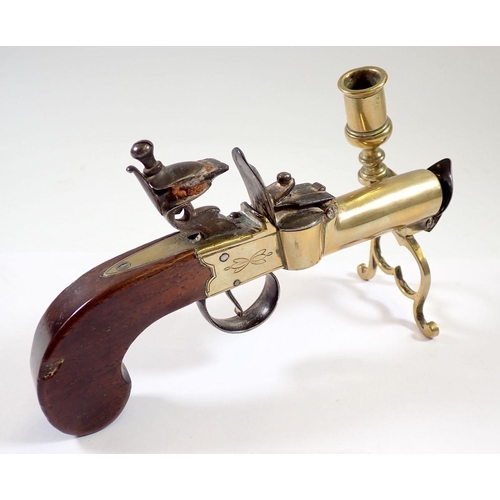 844 - An antique percussion action pistol table lighter with taper stick, 17cm long and a brass stirrup