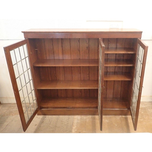 977 - An early 20th century oak lead glazed dwarf bookcase with three doors enclosing shelves, 156cm wide ... 