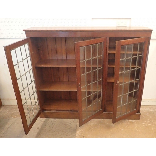 977 - An early 20th century oak lead glazed dwarf bookcase with three doors enclosing shelves, 156cm wide ... 