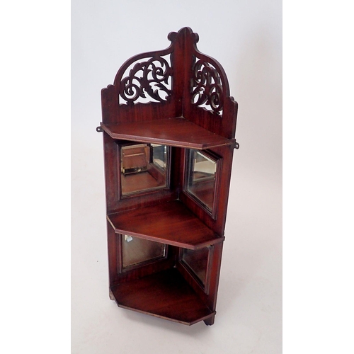 1049 - An Edwardian mahogany set of mirrored corner shelves with decorated pierced surmount, 80cm tall