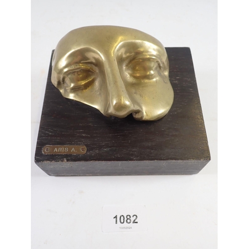 1082 - A Venetian brass face mask mounted on a wooden plinth, 'Aris A' 14 x 12cm