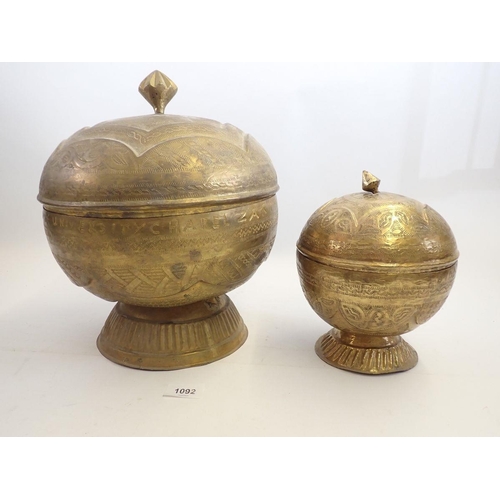 1092 - Two Nigerian 'Bida' brass embossed circular food boxes, largest 30cm tall