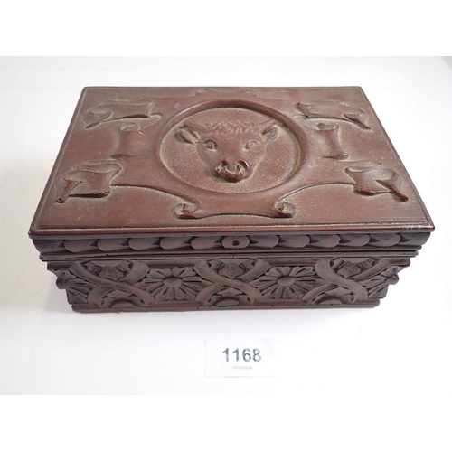 1168 - An antique carved wood box with bulls head to top and floral strap work, 18 x 12cm