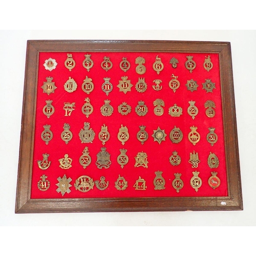 1321 - A framed display of fifty nine numbered regimental military cap badges (Please note - some badges ma... 