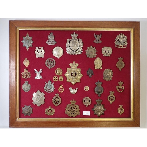 1324 - A framed display of thirty seven military cap badges, helmet plates etc.(Please note - some badges m... 