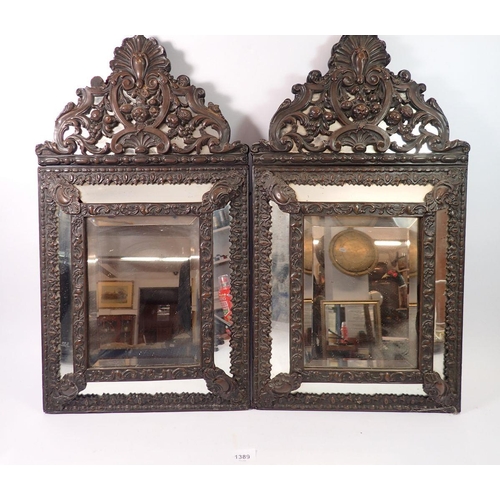 1389 - A pair of Flemish style patinated brass cushion framed mirrors, 59 x 33cm