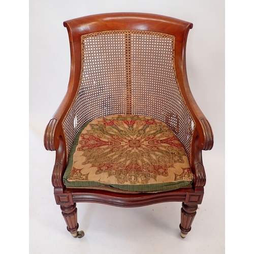 1457 - An early Victorian mahogany and cane library chair with scroll over arms on reeded supports