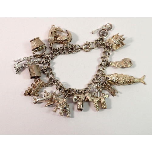 677 - A white metal charm bracelet with white metal and silver charms, 69g