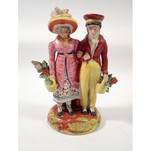 83 - An early Staffordshire group of a man and woman standing with baskets of flowers, 16cm tall