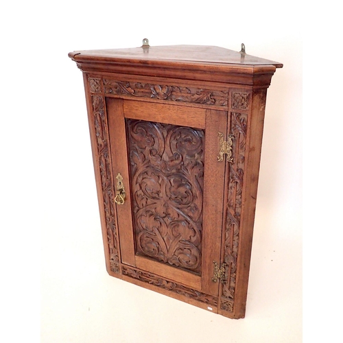 1187 - An oak corner cupboard with carved scrollwork decoration to door, 82cm tall