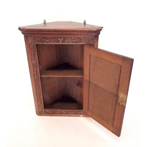 1187 - An oak corner cupboard with carved scrollwork decoration to door, 82cm tall