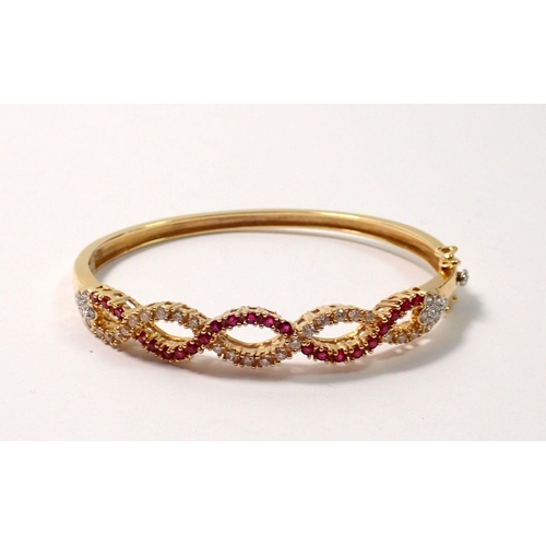 450 - An 18 carat gold hinged bangle with a braided design set diamonds and rubies, 22g