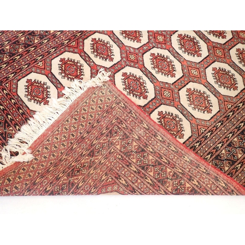 1030 - A Turkoman style rug with three rows of guls on red ground, 185 x 128cm