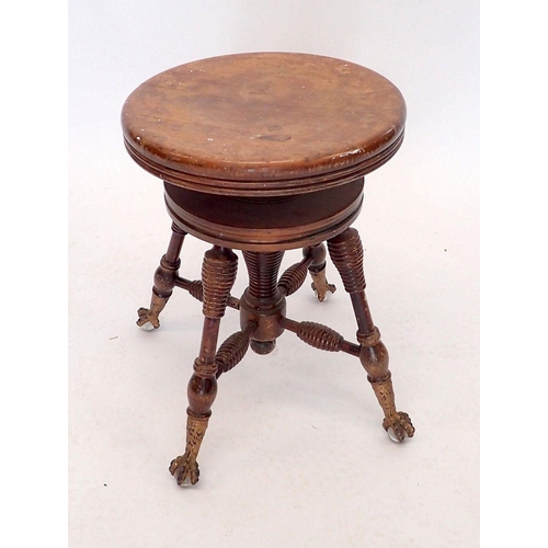 1042 - An American or Canadian mahogany revolving piano stool with gilt metal claw and glass ball feet