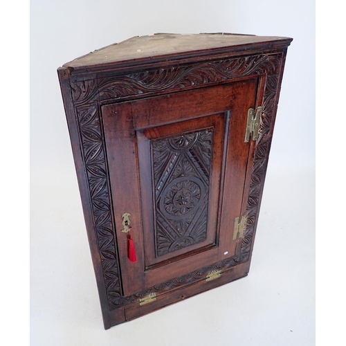 1055 - An antique carved oak wall-hanging corner cupboard, 55cm wide