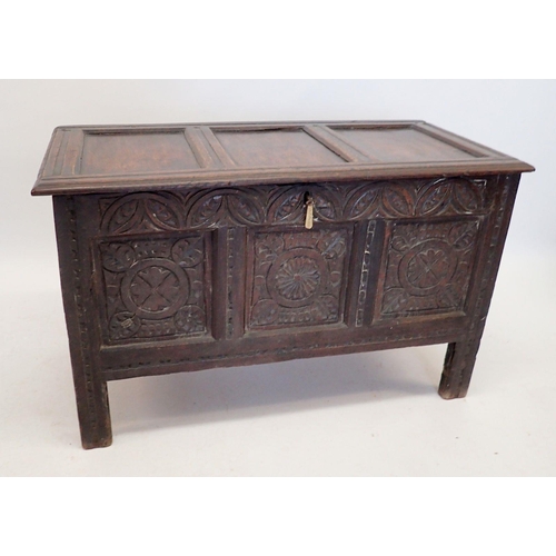 1089 - An antique oak coffer with triple framed plank top and front panels carved stylised flowers and foli... 