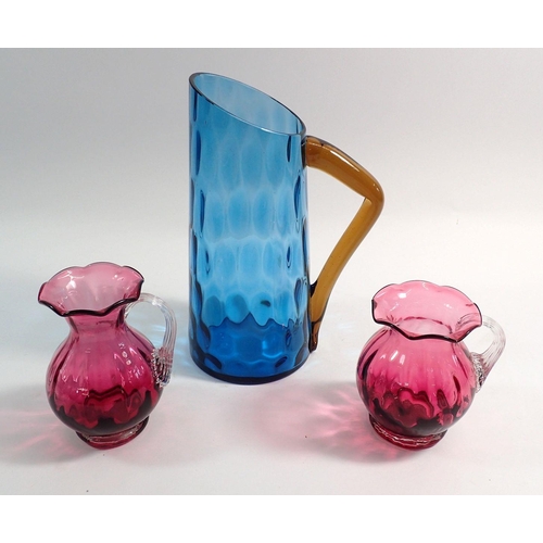 113 - A blue glass jug, 24cm tall and two cranberry jugs