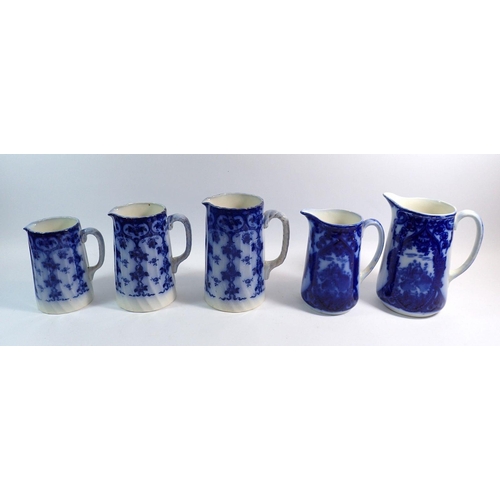 12 - A set of three Edwardian blue and white jugs and two others, tallest 21cm