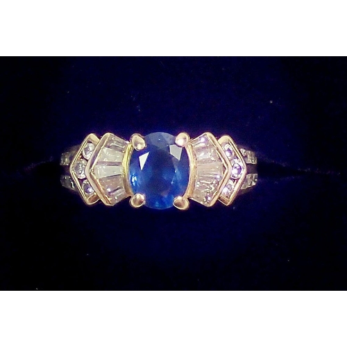 318 - A 9ct gold ring set oval cut blue sapphire on stepped shoulders set baguette and brilliant cut white... 