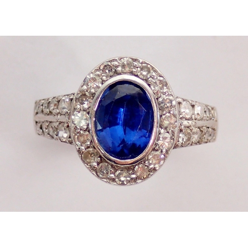 330 - An 18 carat white gold ring set oval cut sapphire within diamond surround and on diamond set shoulde... 