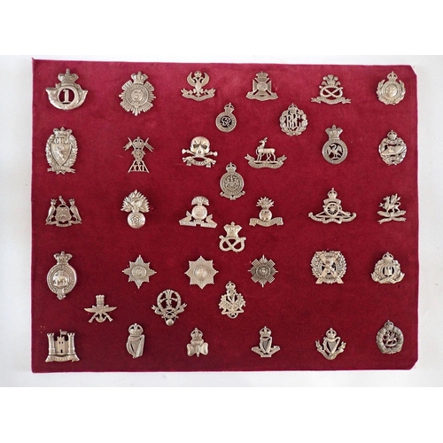 702 - A display of thirty silver military cap badges, marked 'Silver' sample tested as silver, No Frame