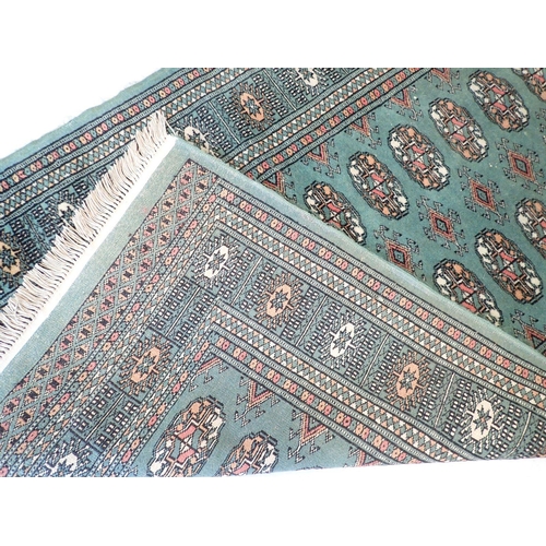 886 - A green ground Turkoman rug with double row of guls 146 x 98cm