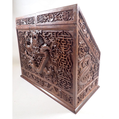 940 - An Indian hardwood slope front correspondence box carved all over dragon and floral decoration, with... 