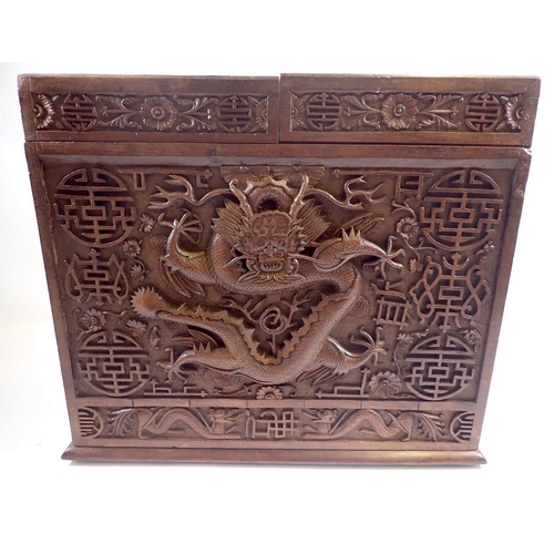 940 - An Indian hardwood slope front correspondence box carved all over dragon and floral decoration, with... 