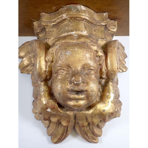 949 - An antique gilt carved wood cherub mask wall bracket with later shaped shelf above, 31cm high