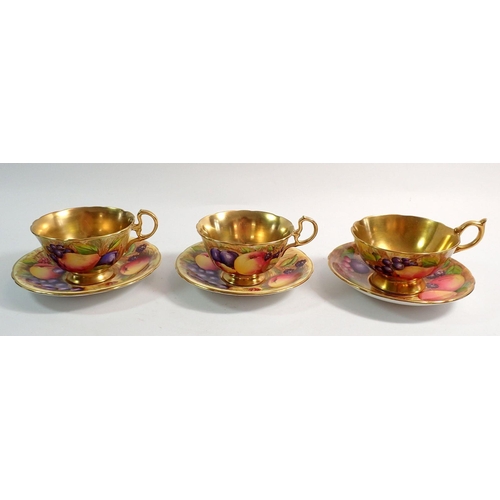 99 - Three Aynsley Orchard Gold cups and saucers painted fruit with two cups and one saucer signed A Jone... 