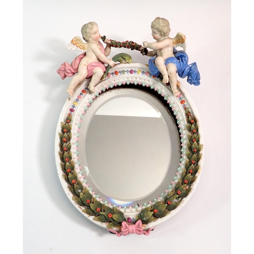 123 - A Sitzendorf style oval mirror with winged cherub surmount and leaf decoration, 29cm tall