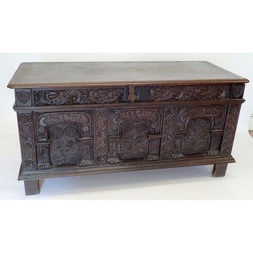 1280 - A large 17th oak coffer with carved triple panelled front and foliage carved sides, 157cm wide