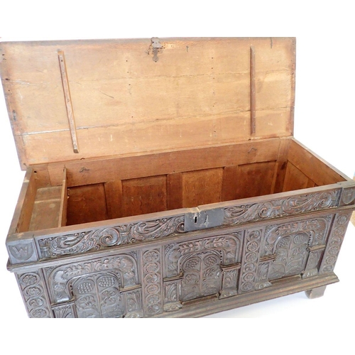 1280 - A large 17th oak coffer with carved triple panelled front and foliage carved sides, 157cm wide