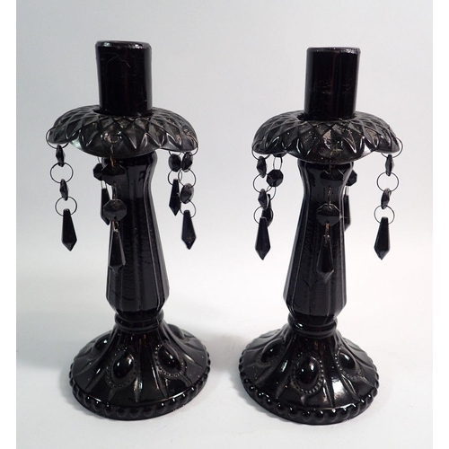 148 - A pair of Victorian black moulded glass candlesticks with lustres, 26cm