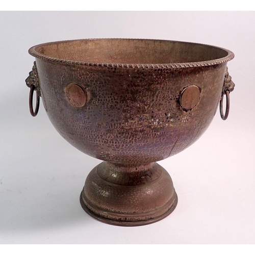 186 - A hammered copper pedestal punch bowl with lion mask ring handles and applied William halfpenny coin... 