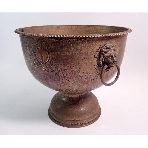 186 - A hammered copper pedestal punch bowl with lion mask ring handles and applied William halfpenny coin... 