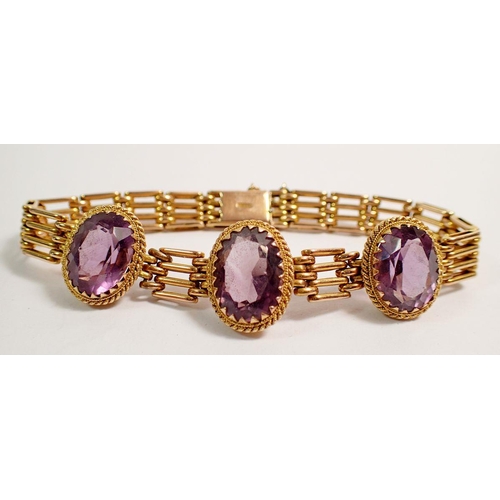 438 - A 9 carat gold gatelink bracelet set three oval cut amethysts, 20g