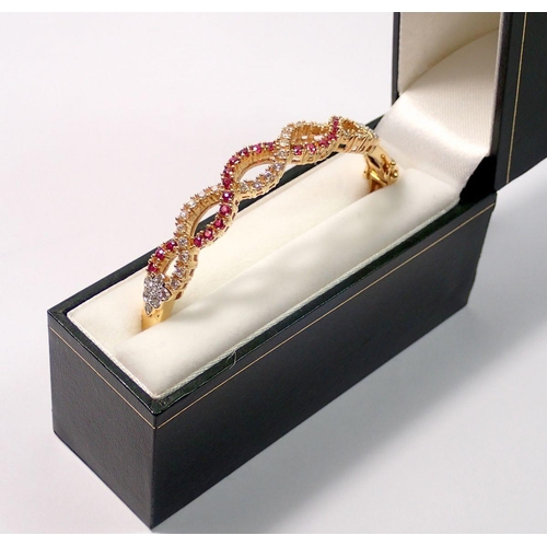 439 - An 18 carat gold hinged bangle with a braided design set diamonds and rubies, 22g