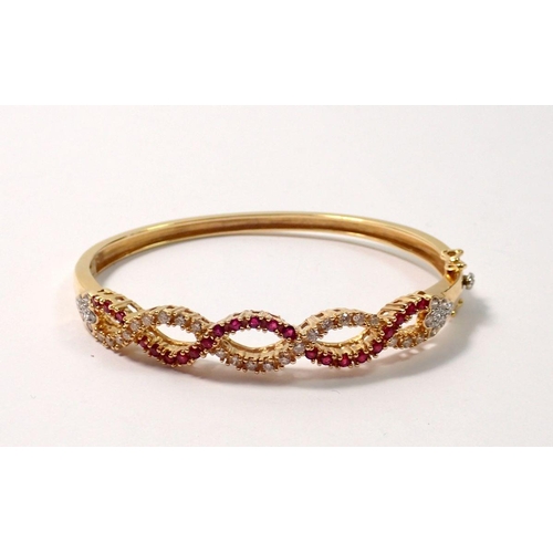 439 - An 18 carat gold hinged bangle with a braided design set diamonds and rubies, 22g