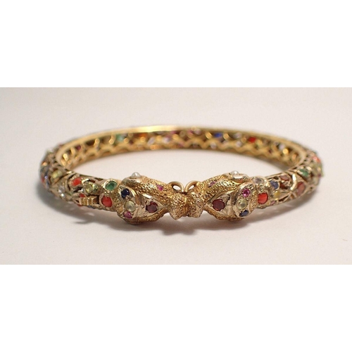 442 - A 9 carat gold Eastern pierced hinged bangle with elephant head terminals set semi precious stones, ... 