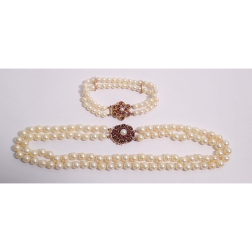 486 - A two strand pearl necklace and similar bracelet, both with 14 carat gold clasps set garnets, neckla... 