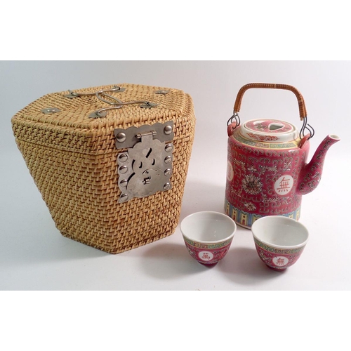 109 - A Chinese export teapot and two cups in fitted wicker case, 20cm tall