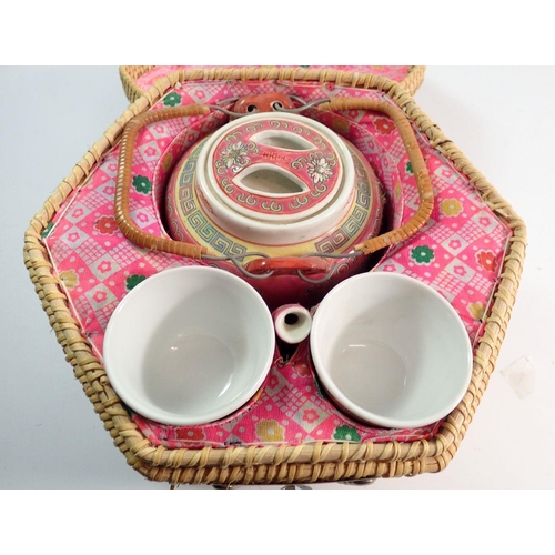 109 - A Chinese export teapot and two cups in fitted wicker case, 20cm tall