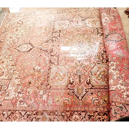 1286 - A large early 20th century Persian Heriz carpet with geometric motifs on a pink ground, made in Iran... 