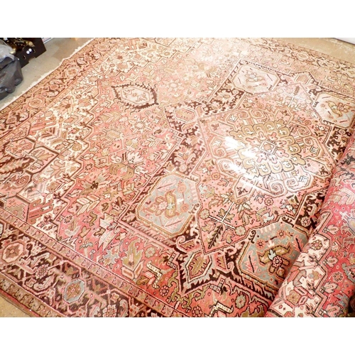 1286 - A large early 20th century Persian Heriz carpet with geometric motifs on a pink ground, made in Iran... 