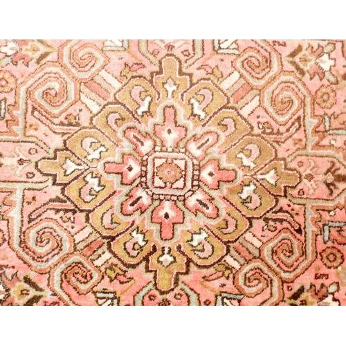 1286 - A large early 20th century Persian Heriz carpet with geometric motifs on a pink ground, made in Iran... 