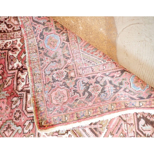 1286 - A large early 20th century Persian Heriz carpet with geometric motifs on a pink ground, made in Iran... 